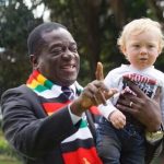 A snap picture of Zimbabwe President Emmerson Mnangagwa holding a baby while pointing to the camera.