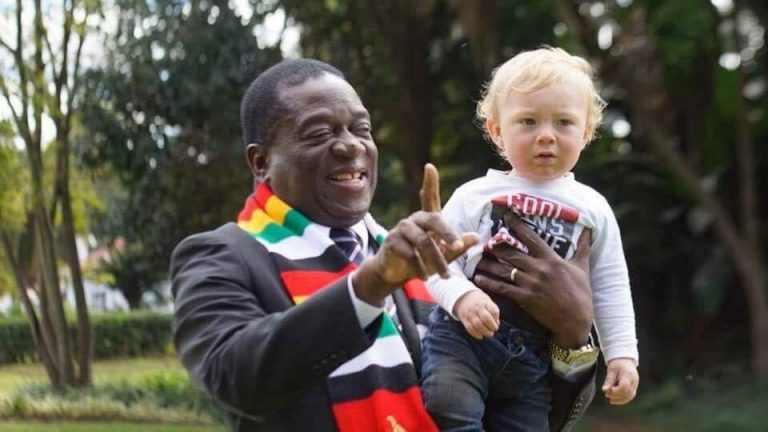 A snap picture of Zimbabwe President Emmerson Mnangagwa holding a baby while pointing to the camera.