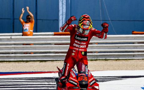 Ducati rider Pecco Bagnaia celebrating a win after completing a MotoGP race.