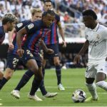 Real Madrid forward Vinicius Junior vies with Barcelona's Sergi Roberto (L) and Jules Kounde (C) during the Spanish League football match between Real Madrid CF and FC Barcelona at the Santiago Bernabeu stadium on 16 October 2022.