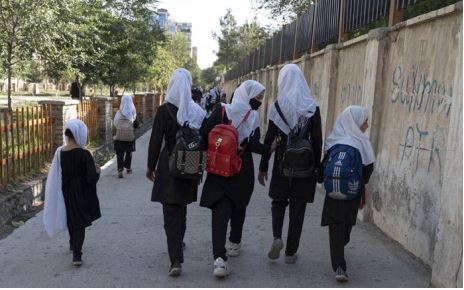 In this picture taken on 9 August 2022, Afghan primary schoolgirls walk to their school along a street in Kabul after Taliban takeover.