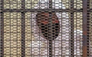 Egyptian media and real estate tycoon Mohamed el-Amin looks from the defendant's cage during a trial session over charges of "human trafficking" and "sexual assault" in the Egyptian capital's eastern suburb of New Cairo on March 20, 2022.