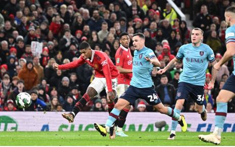 Manchester United's English striker Marcus Rashford (L) shoots and scores his team second goal during the English League Cup fourth round football match between Manchester United and Burnley, at Old Trafford, in Manchester, on 21 December 2022.