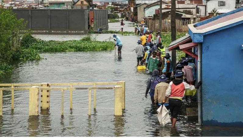 A file photo shows people walk through flood water after several houses were affected by rising water following heavy rains in 67 Hectares neighbourhood in Antananarivo, Madagascar on January 24, 2022. (AFP)
