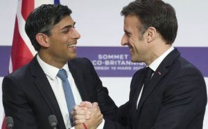 Britain's Prime Minister Rishi Sunak (L) and France's President Emmanuel Macron (L) react as they shake hands during a joint press conference at the end of the French-British summit, at the Elysee Palace, in Paris, on 10 March 2023.