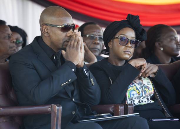Late and former Zimbabwean president Robert Mugabe's daughter Bona Mugabe (R) and his spouse Simba Chikore (L) watch as the coffin of Mugabe is ready to be lowered in a grave in Harare, Zimbabwe, on September 28, 2019.