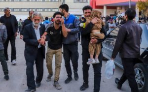 People injured in two explosions in quick succession that struck a crowd marking the anniversary of the 2020 killing of Guards general Qasem Soleimani, are helped outside a hospital in the southern Iranian city of Kerman on January 3, 2024. (Photo by SARE TAJALLI / ISNA / AFP)